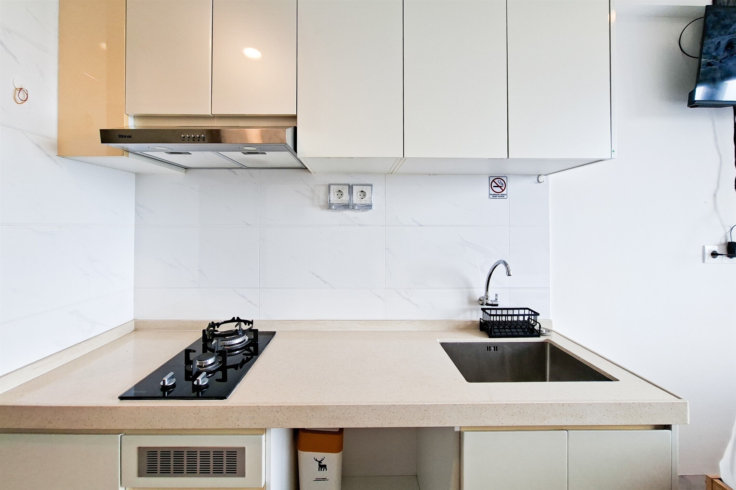 Een moderne keuken met een gasfornuis, een roestvrijstalen spoelbak en witte keukenkastjes.
