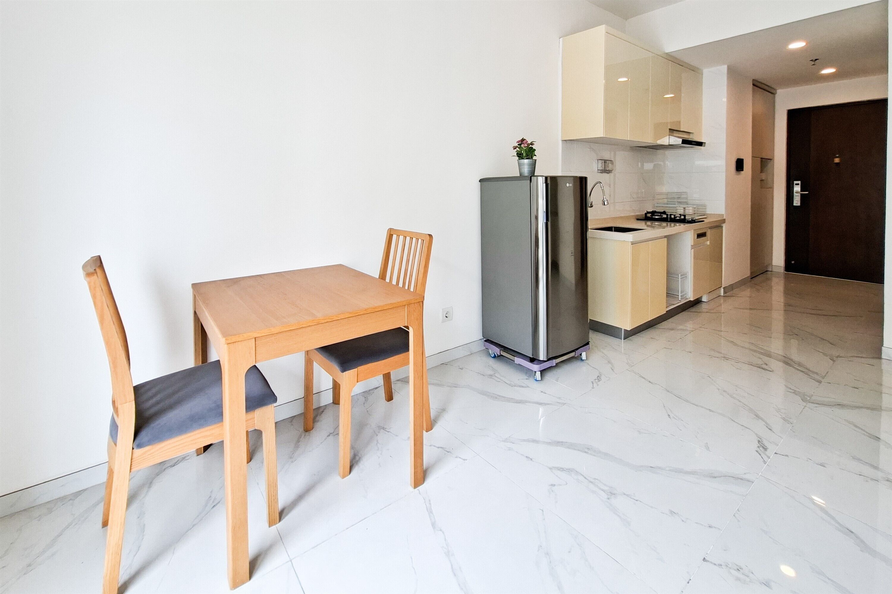 Une cuisine compacte avec une table et des chaises en bois, un réfrigérateur en acier inoxydable et un petit plan de travail.