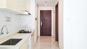 A modern kitchen with a sink, stove, and cabinets. - Neat 2Br For 3 Pax At Sky House Bsd Apartment (Pagedangan)