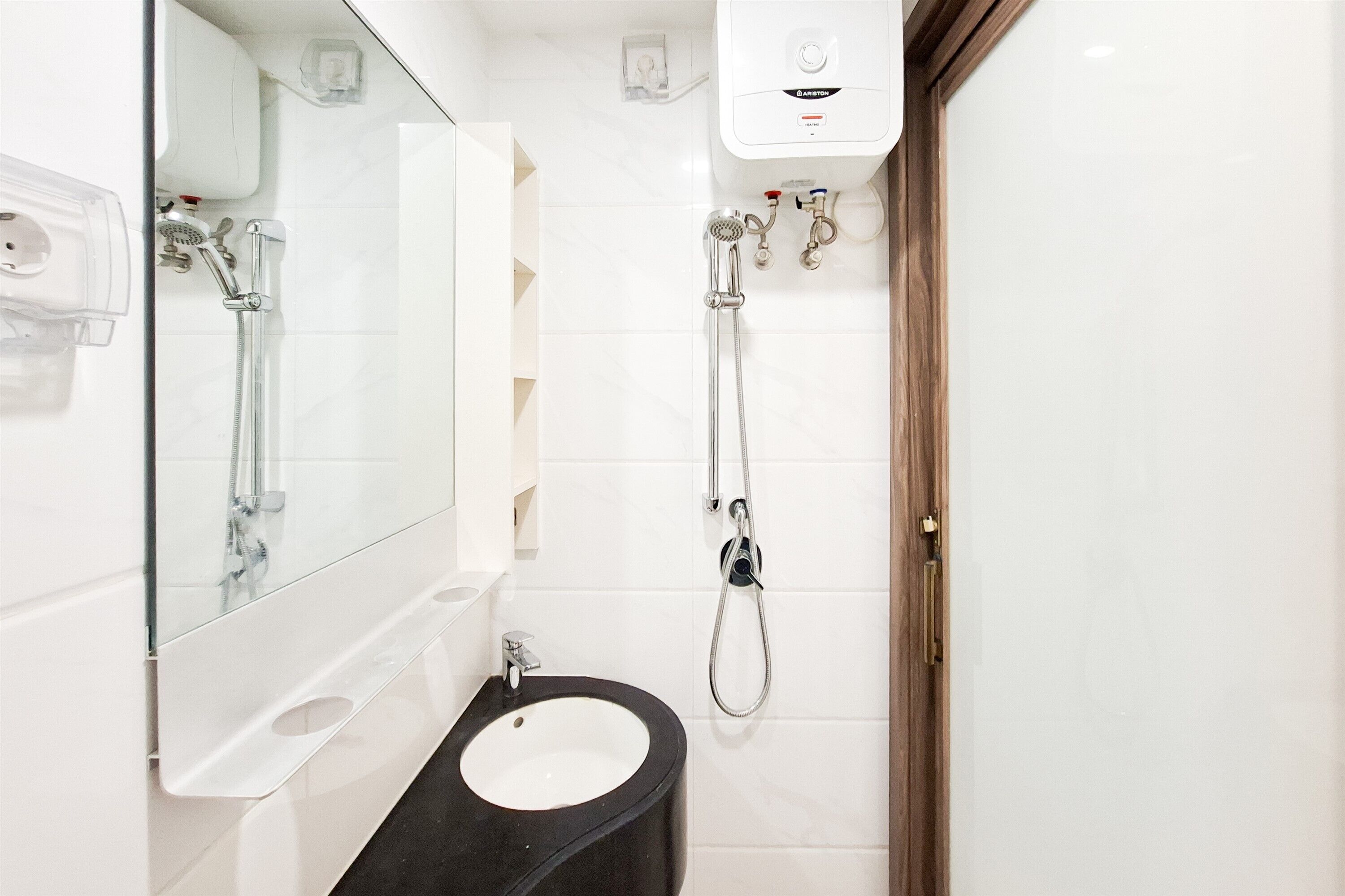 A bathroom with a white sink, a mirror, a shower with a handheld showerhead, and a toilet.