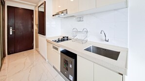 A modern kitchen with a dishwasher, a sink, and a stove. - Studio With Simple Style At Sky House Bsd Apartment (Pagedangan)