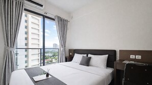 A hotel room with a large bed, a bedside table, a chair, a window with curtains, and a view of a cityscape. - Studio With Simple Style At Sky House Bsd Apartment (Pagedangan)