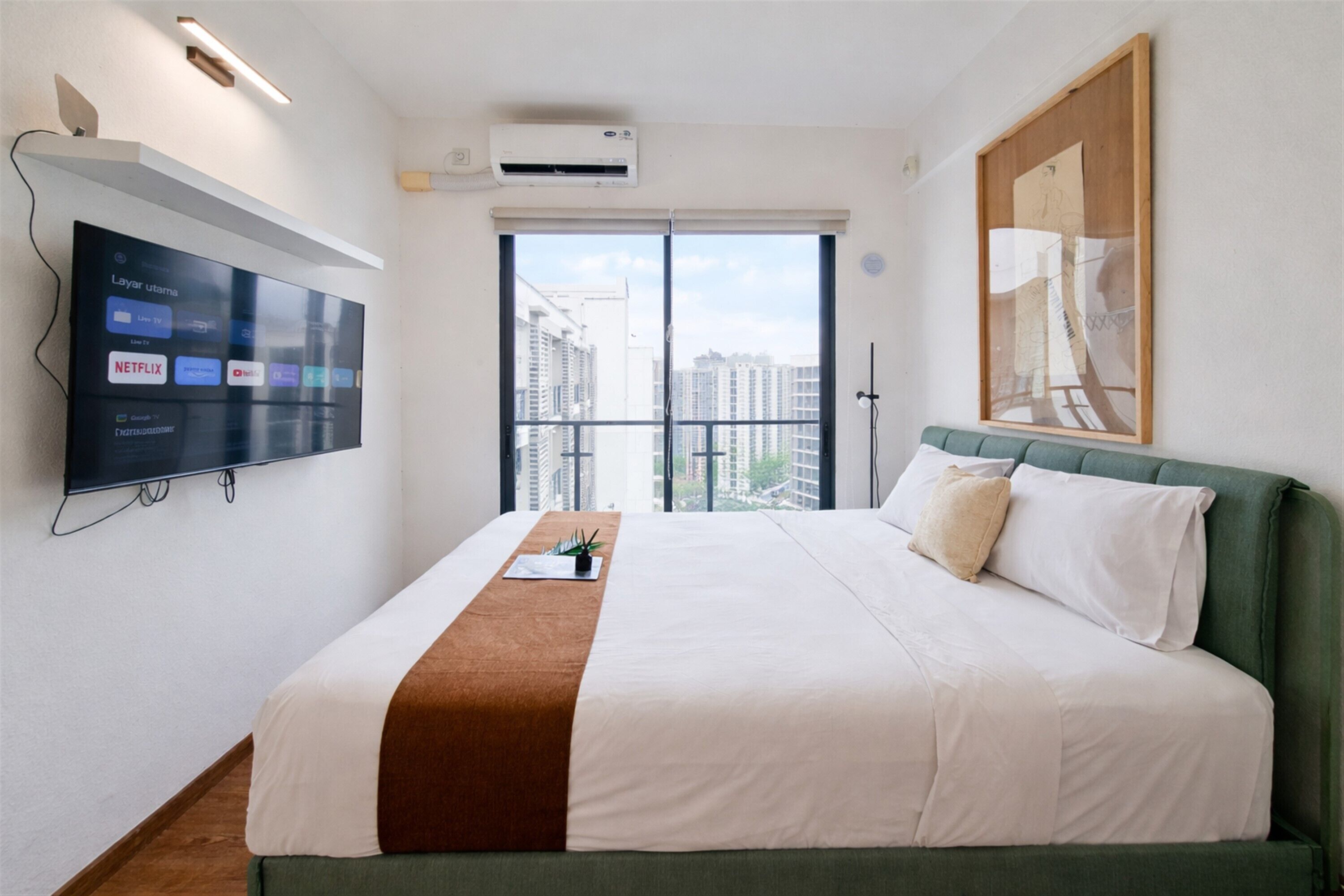 Une chambre d’hôtel équipée d’un lit, d’un téléviseur fixé au mur permettant d’accéder à des services de diffusion en continu, d’une fenêtre donnant sur la ville et d’un système de climatisation.