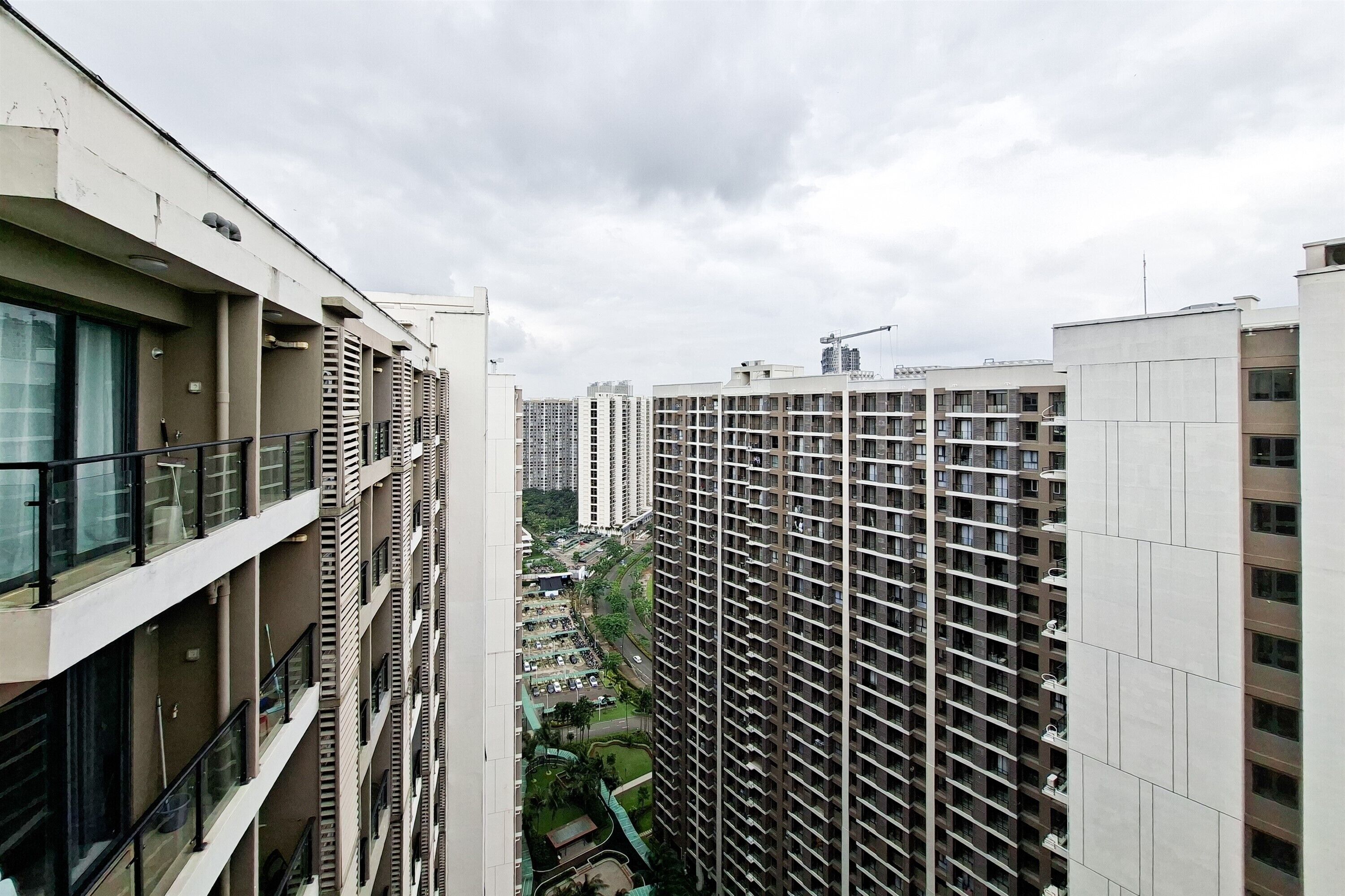 A high-rise residential building with multiple balconies, a construction crane in the background, and a view of the surrounding area.