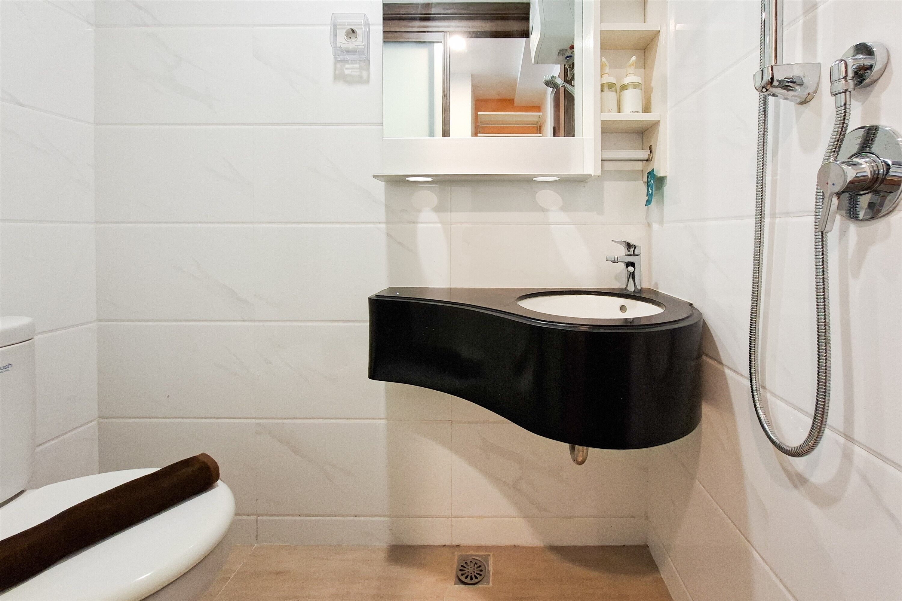 A bathroom with a toilet, a sink, a mirror, and a shower.