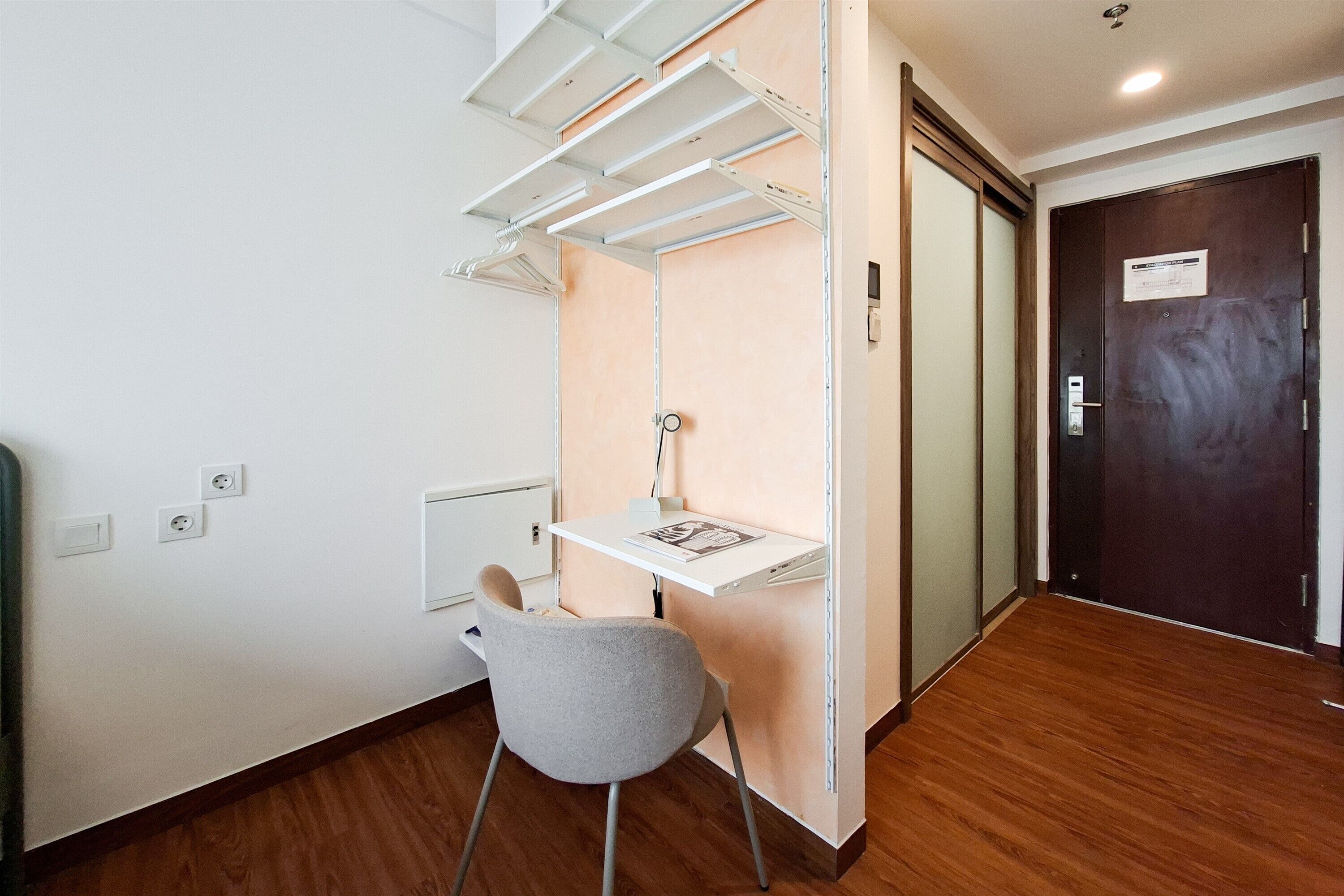 Habitación compacta con escritorio, silla y un tendedero de pared.