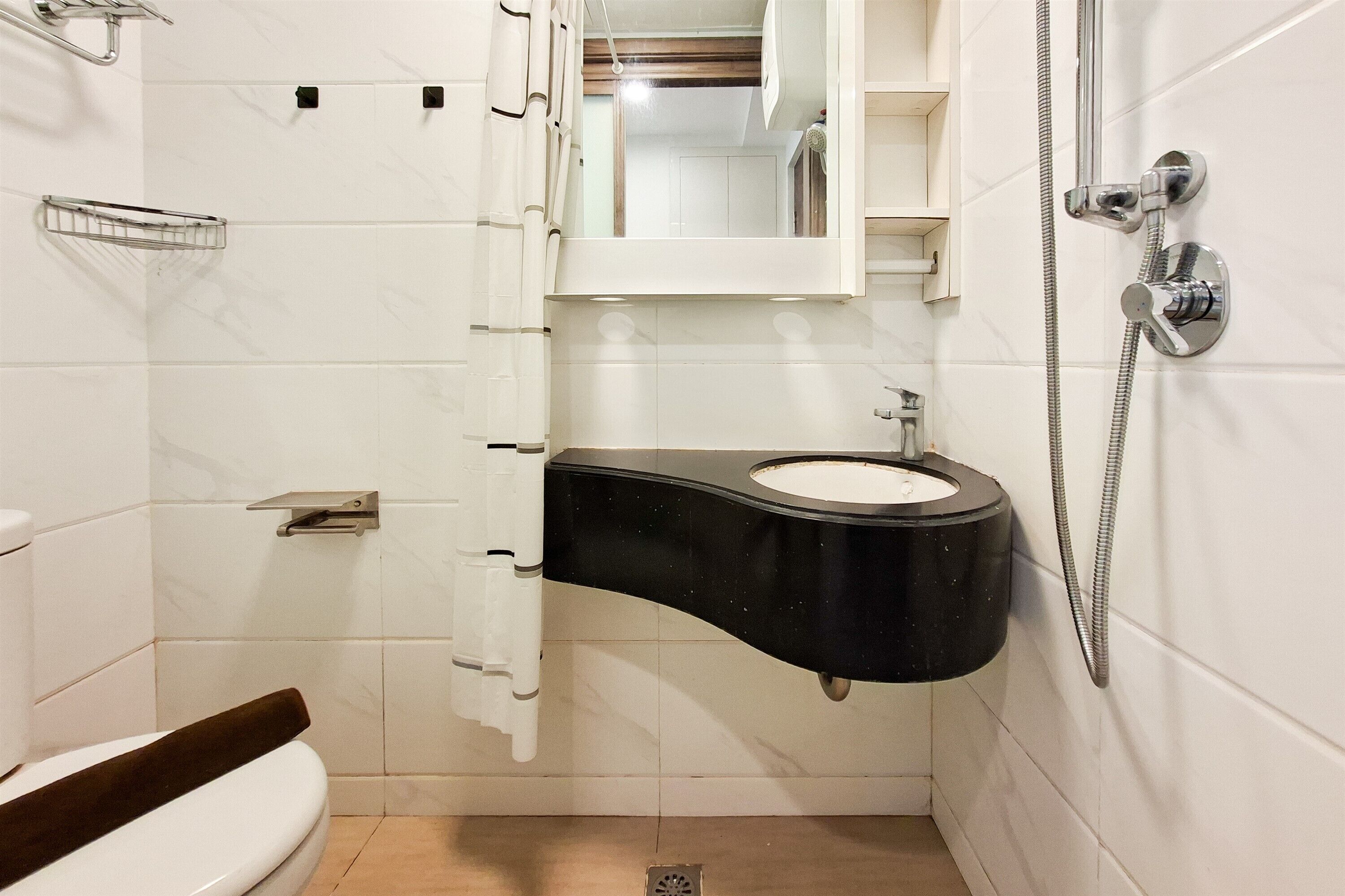 Ein Badezimmer mit einem schwarzen Waschbecken, weißen Fliesen, einer Dusche und einer Toilette.