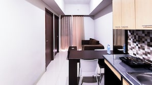 A compact kitchen with a dining area, a sofa, and a water bottle on the counter. - Compact And Warm 2Br At Apartement Skyland City Jatinangor (Hegarmanah)