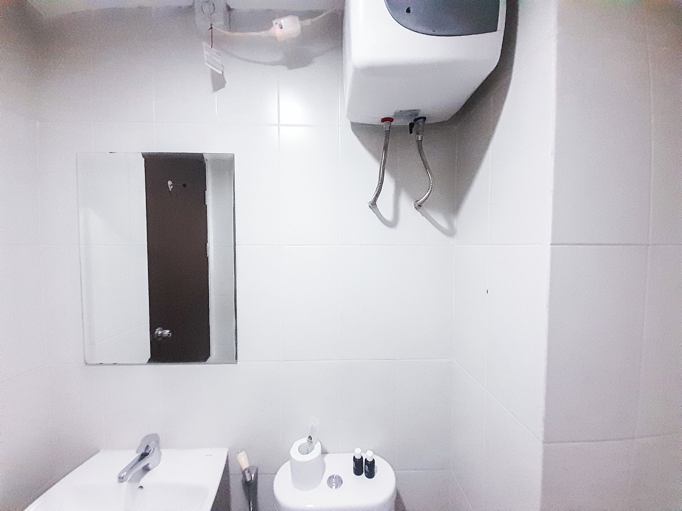 A bathroom with a sink, toilet, and hand dryer.