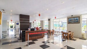 A hotel lobby with a reception desk, check-in counters, a dining area with tables and chairs, and large windows offering views of the outdoors. - Compact And Warm 2Br At Apartement Skyland City Jatinangor (Hegarmanah)