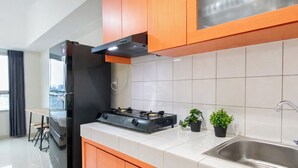 A modern kitchen with a gas stove, stainless steel sink, and wooden cabinets. - Pleasant And Restful Studio At Apartment Springlake Summarecon Bekasi (Bekasi)
