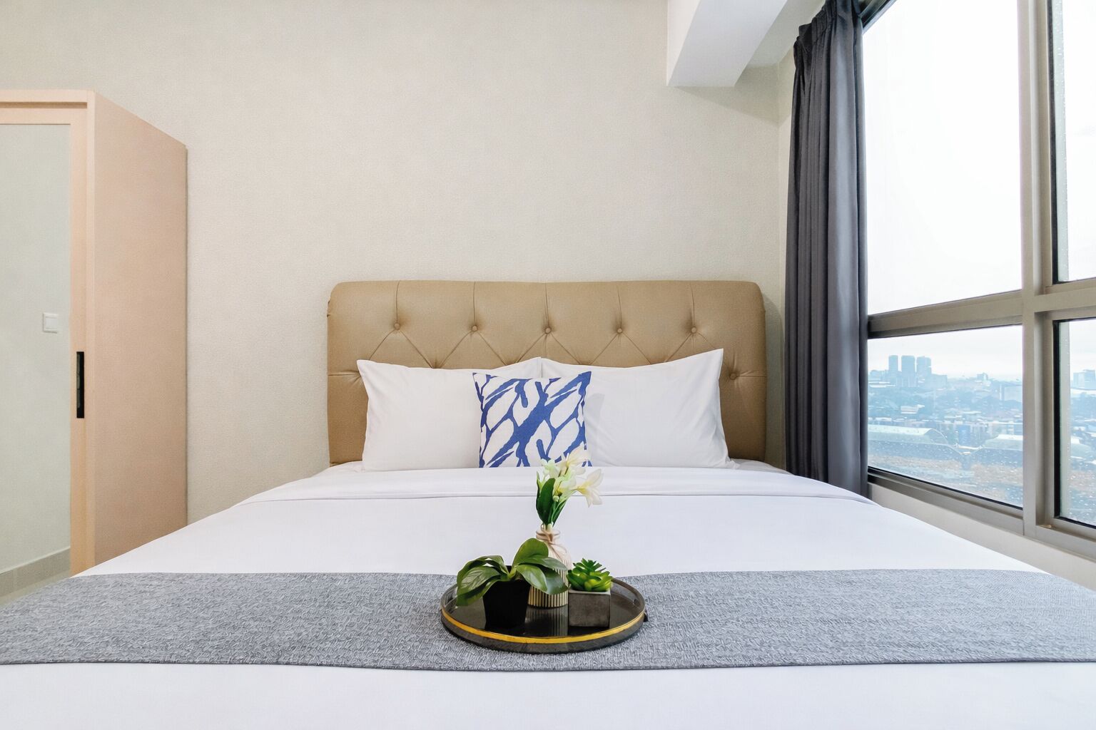 A hotel room with a large bed, a view of the city, and a window with curtains.
