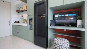 A modern kitchen with a built-in refrigerator, a coffee machine, and a flat-screen TV displaying streaming services. - Chic And Cozy Studio Space At Apartment Springlake Summarecon Bekasi (Bekasi)