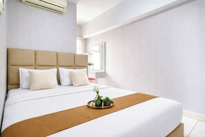 A hotel room with a large bed, a headboard, a window, and a small table with a plant. - 2Br Apartment At Springlake Summarecon Bekasi (Bekasi)