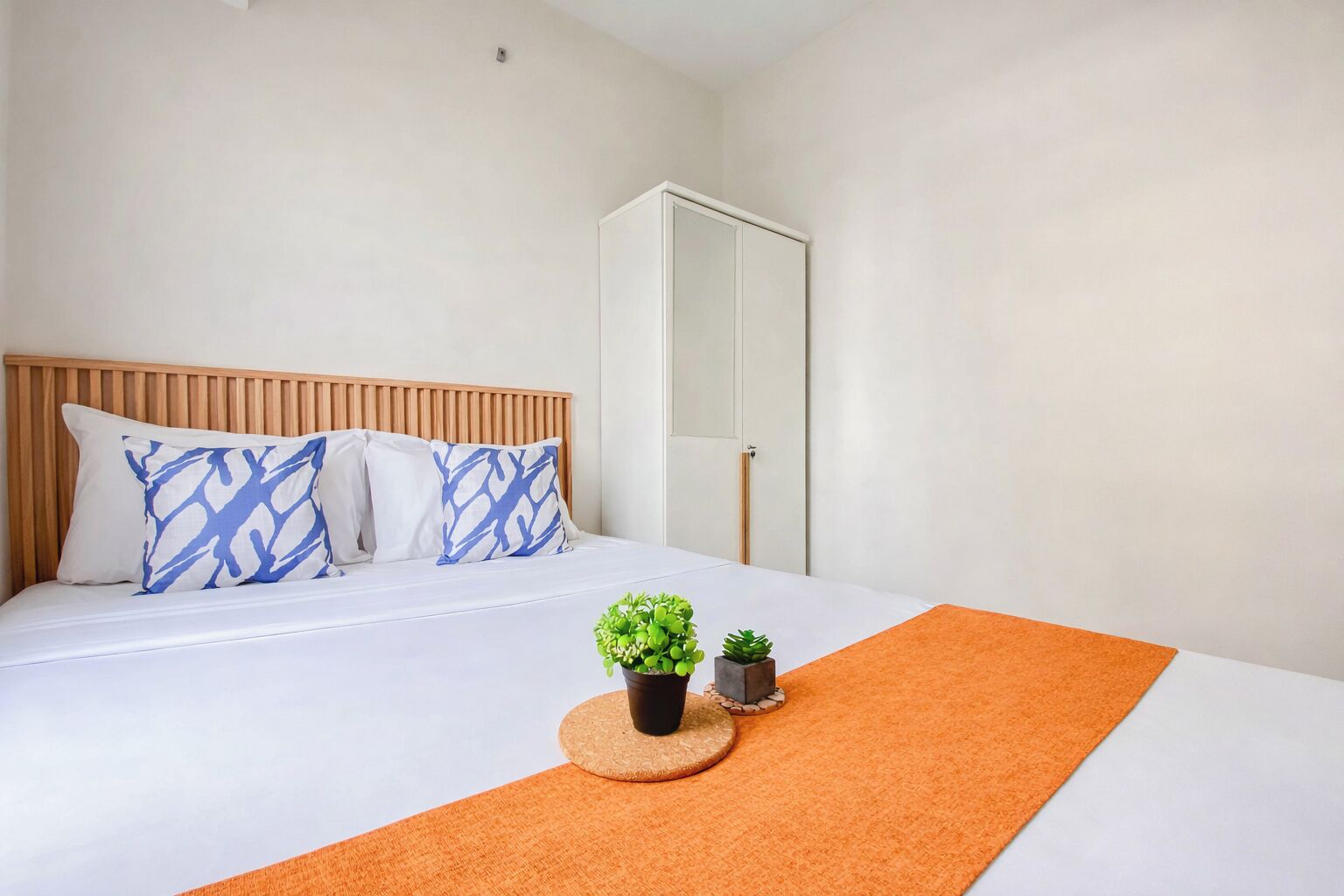 Ein Hotelzimmer mit einem Bett, einem Kleiderschrank und einem kleinen Topfpflanzen auf einer runden Matte.