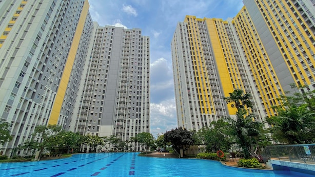A high-rise residential building with a swimming pool in the foreground. - Fully Furnished 2Br Apartment At Springlake Summarecon Bekasi (Bekasi)