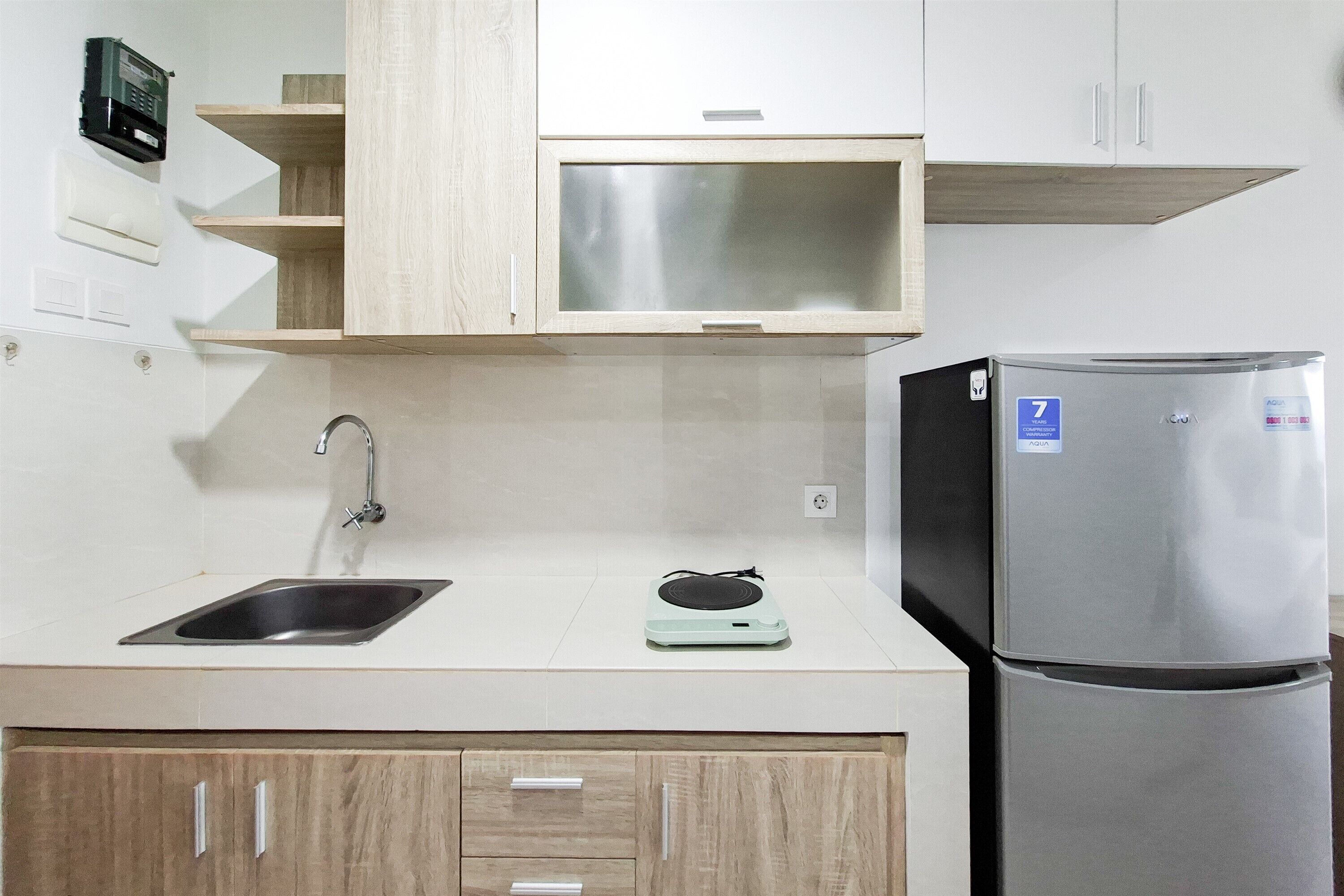 A kitchen with a stainless steel refrigerator, a sink, and wooden cabinets.