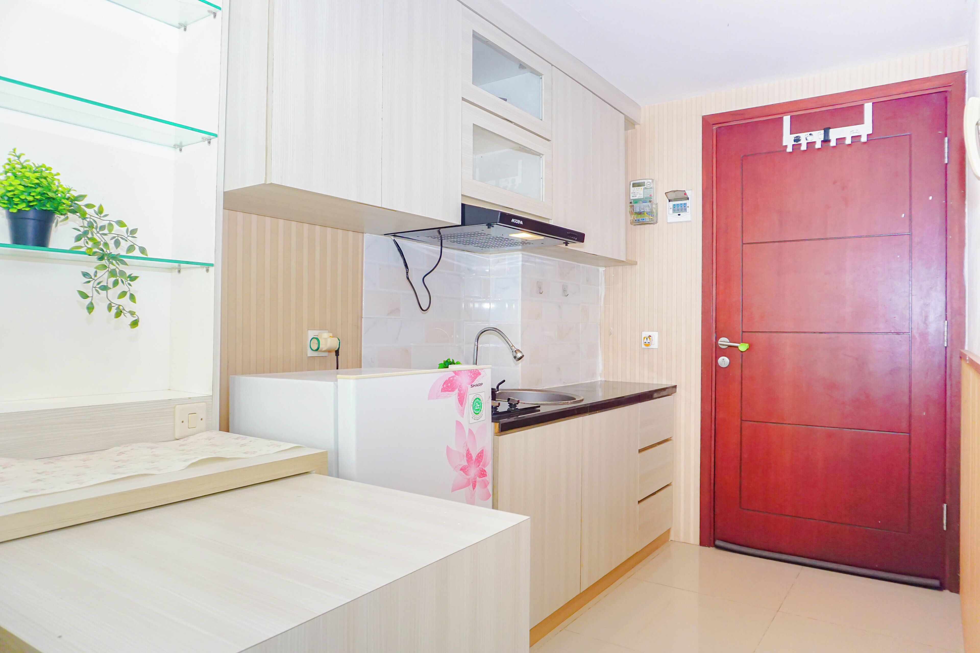 A kitchen with a white countertop, a red door, and a small potted plant on a shelf.