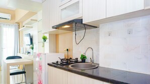 A modern kitchen with a built-in stove, sink, and ventilation hood. - Comfortable And Pleasant Studio At Apartment Tamansari Mahogany Karawang (Karawang)