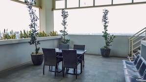A rooftop terrace with a table and chairs, potted plants, and a view of the city. - Comfortable And Pleasant Studio At Apartment Tamansari Mahogany Karawang (Karawang)
