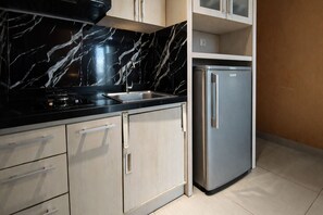 A kitchen with a black marble countertop, stainless steel appliances, and light wood cabinets. - Neat 2Br For 3 Pax At Tamansari Papilio Apartment (Surabaya)