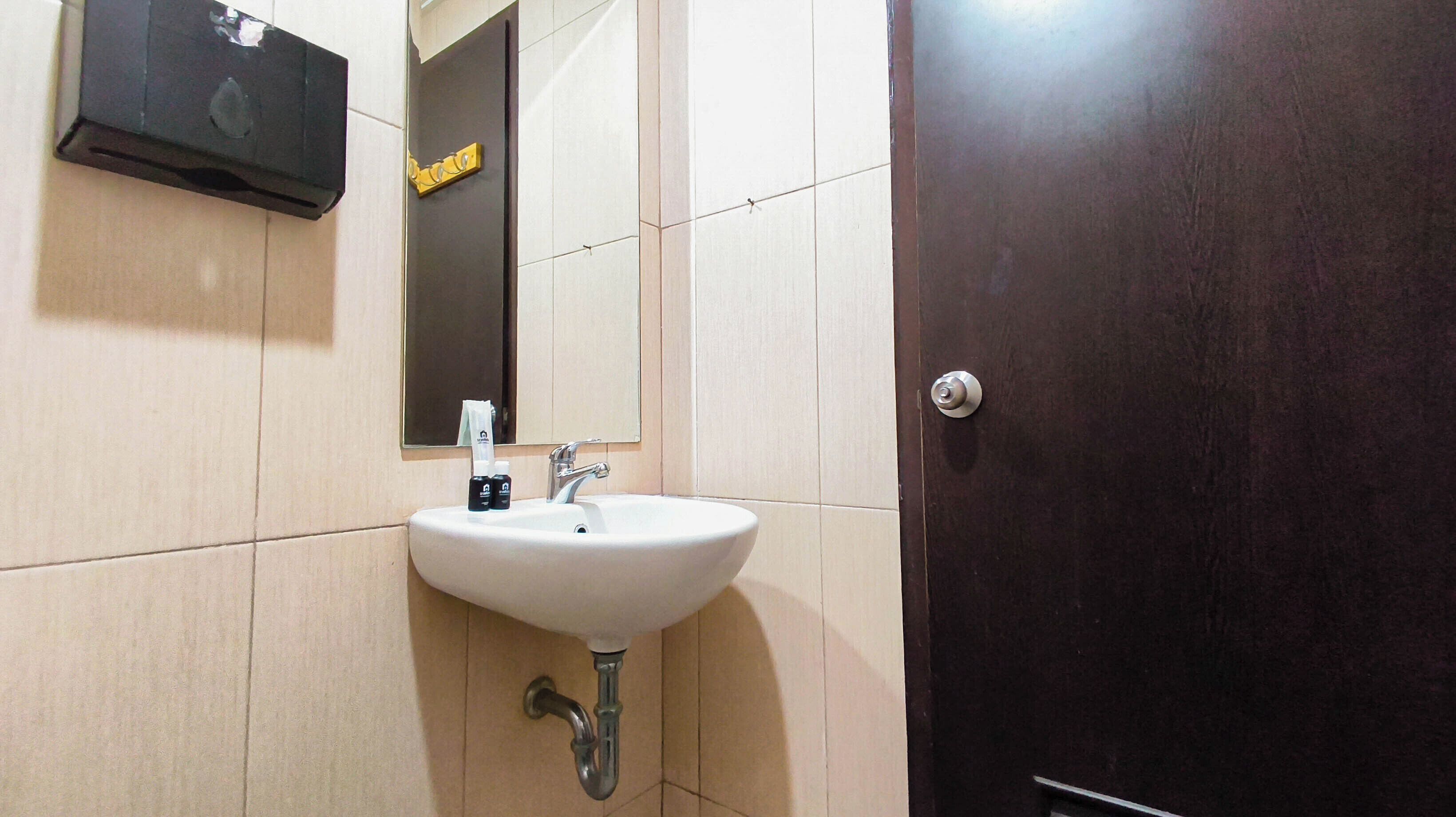 A bathroom with a white sink, a mirror, and a dark wooden door.