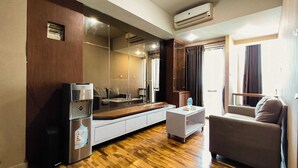 Et moderne hotelværelse med sofa, et lille bord, et køleskab og en stol.