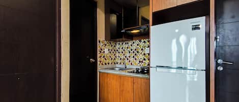 Una cocina compacta con refrigerador, lavamanos y salpicadero de azulejos.