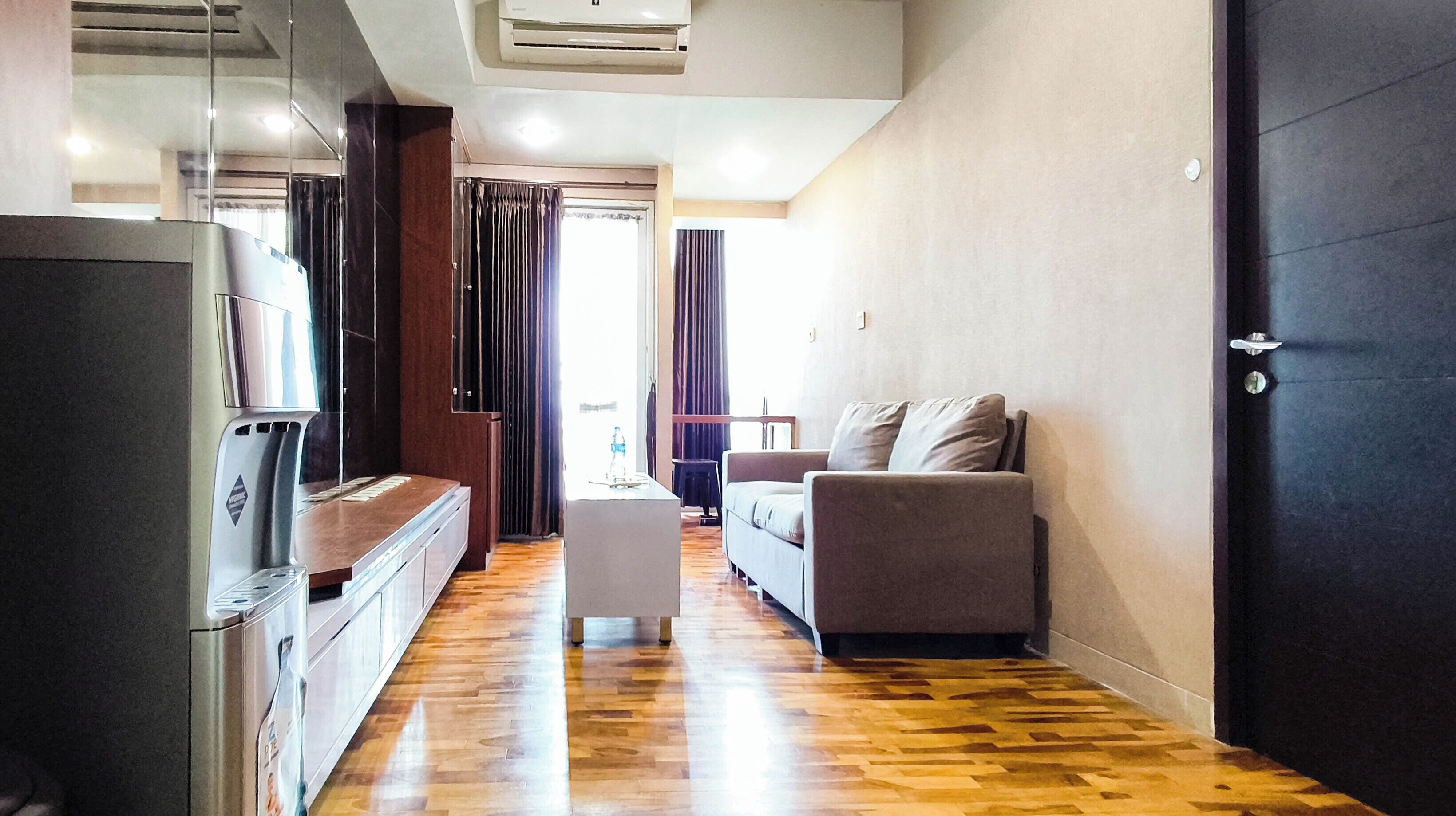 Una sala moderna con un sofá, una mesa de centro y una zona de cocina con refrigerador.