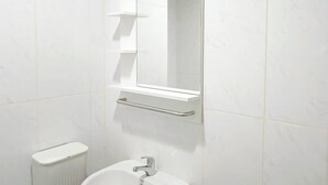 A bathroom with a white sink, a mirror, and a toilet. - Wooden Touch Studio At Tamansari Skylounge Makassar Apartment (Makassar)