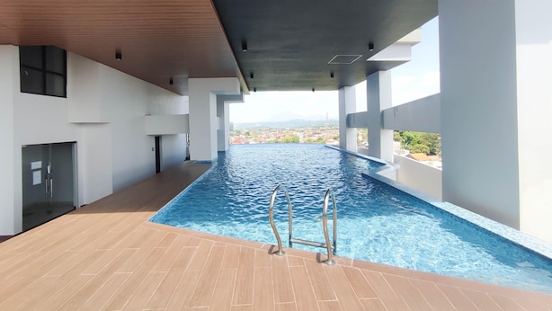 Piscina interna moderna con acqua cristallina, pavimento in legno e vista sulla città.