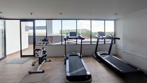 Una palestra con tapis roulant e attrezzature per esercizi, ampie finestre e vista esterna.