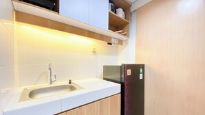 A modern kitchen with a sink, cabinets, and a refrigerator. - Best Deal Corner Studio Apartment At The Alton (Semarang)