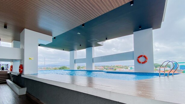 An indoor swimming pool with clear views of the surrounding landscape, a lifebuoy, and a metal ladder. - Best Deal Corner Studio Apartment At The Alton (Semarang)
