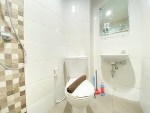 A bathroom with a toilet, a shower, a sink, and a mirror. - Best Deal Corner Studio Apartment At The Alton (Semarang)