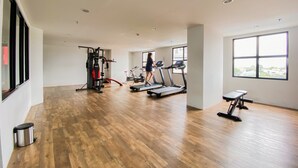 A gym with treadmills, a weight machine, and a bench. - Best Deal Corner Studio Apartment At The Alton (Semarang)