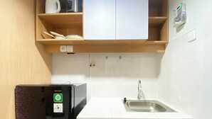 Eine kleine Küche mit Kühlschrank, Spüle und Holzschränken.