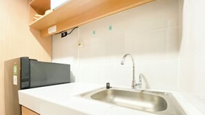 Eine moderne Küche mit Spüle aus Edelstahl, einer weißen Arbeitsplatte und Holzschränken.