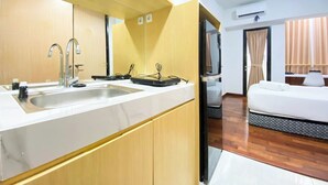 A modern hotel room with a kitchen area, a bed, and a TV. - Modern Look Studio At The Alton Apartment (Semarang)
