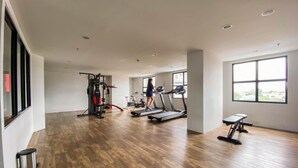 A spacious gym with treadmills, a weight machine, and a bench. - Modern Look Studio At The Alton Apartment (Semarang)