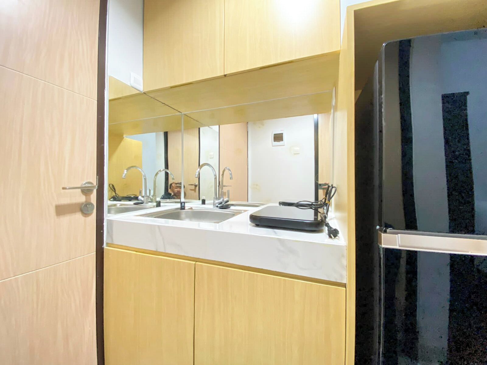 Un baño con dos lavamanos, un espejo y un refrigerador negro.