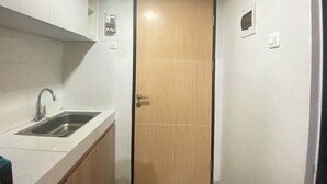 Une petite cuisine compacte, équipée d’un évier, de placards et d’une porte.