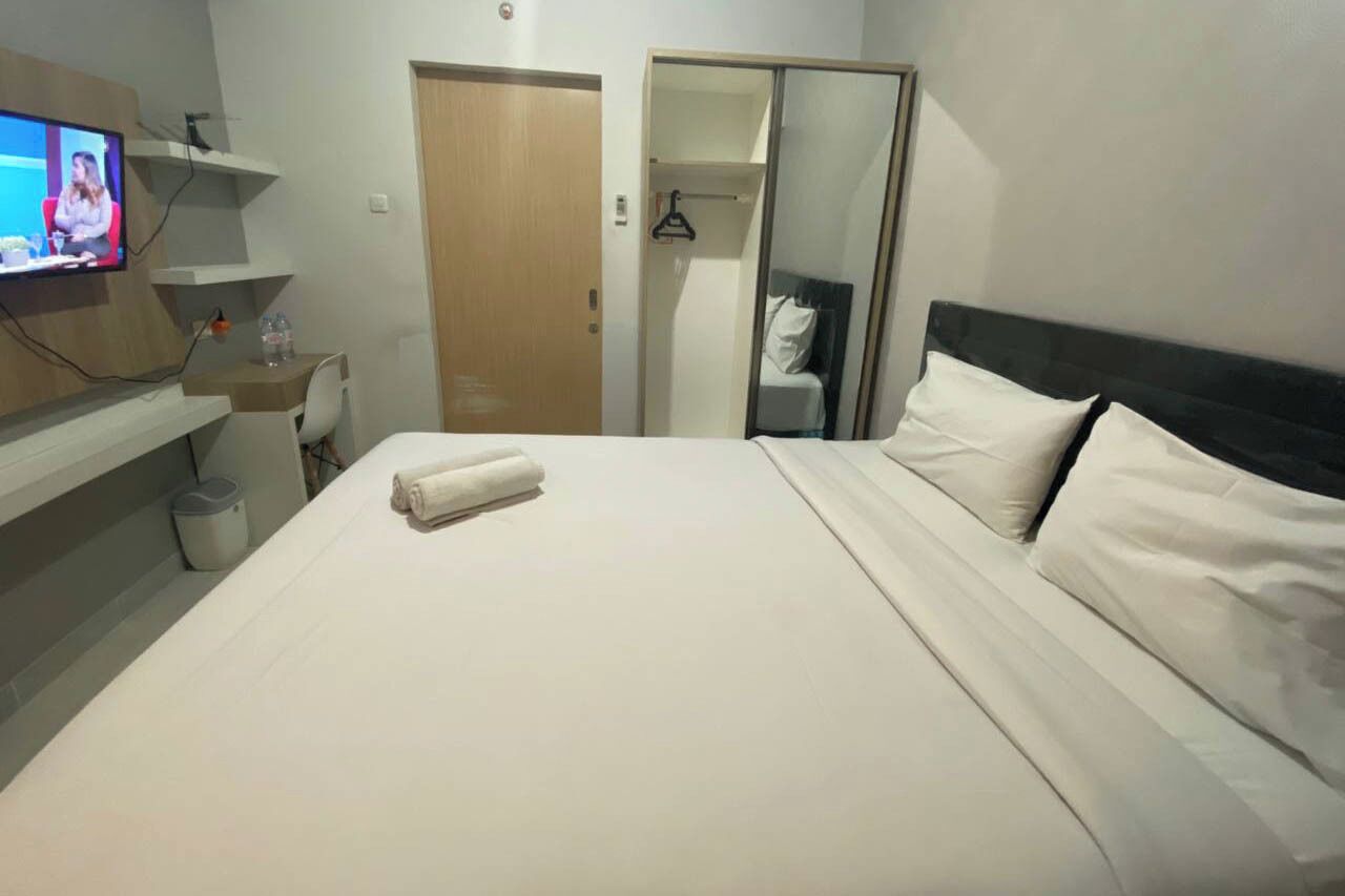 Una habitación de hotel con cama, televisión, escritorio y armario.