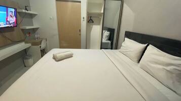 Una habitación de hotel con cama, televisión, escritorio y armario.