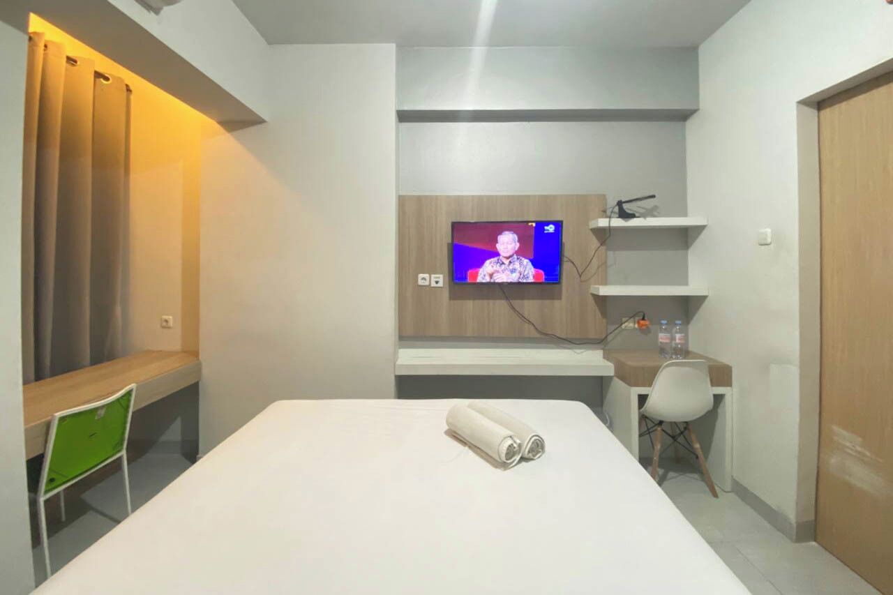 Une chambre d’hôtel équipée d’un lit, d’un bureau, d’une chaise, d’un téléviseur fixé au mur et d’un rideau.