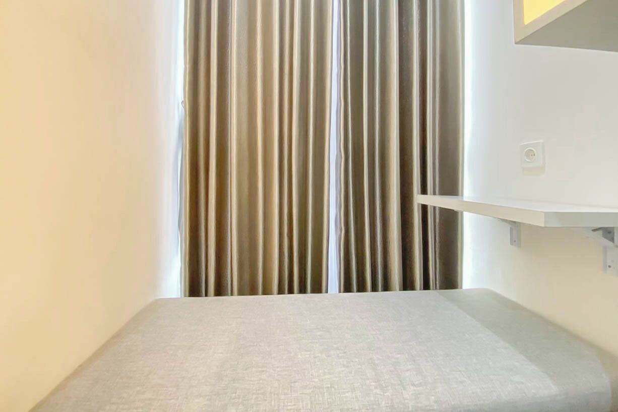 Une pièce comprenant un lit, une étagère fixée au mur et une fenêtre équipée de stores verticaux.