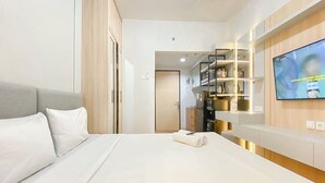 Une chambre d’hôtel  équipée d’un lit, d’un téléviseur fixé au mur et d’un coin cuisine.