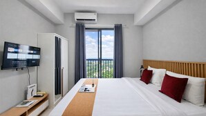 Ein Hotelzimmer mit Bett, Wandfernseher, Kleiderschrank und einem fenster mit Vorhängen.