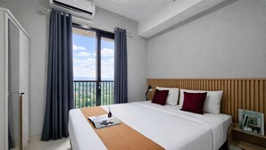 Ein Hotelzimmer mit einem großen Bett, einem Holzkopfteil, einem Nachttisch, einer Zeitschrift und einem Fenster mit Vorhängen.