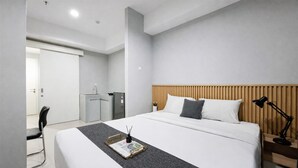 Moderni hotellihuone, jossa on suuri sänky, puinen pääty, yöpöytä lampun kanssa ja tuoli.
